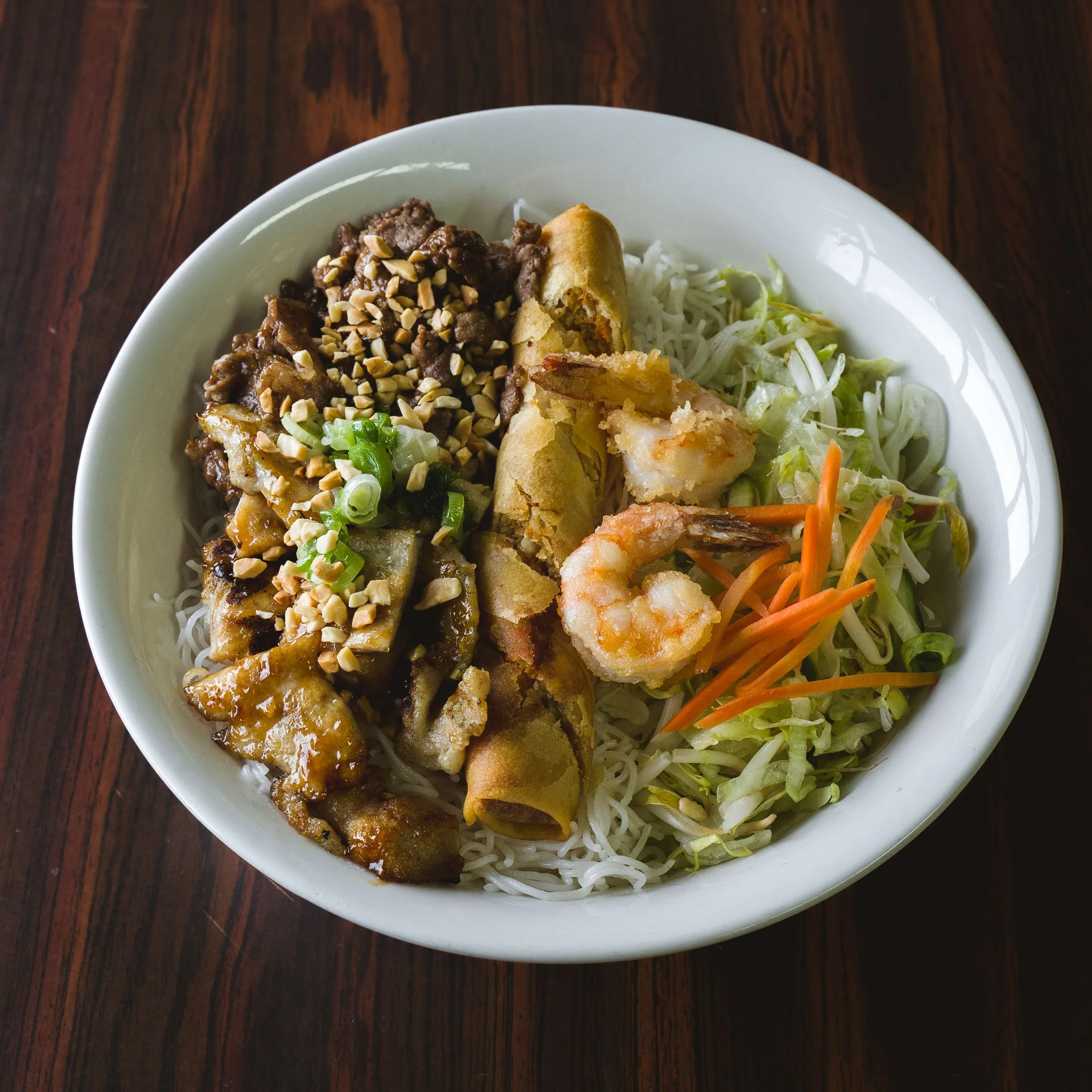 Vietnamese vermicelli bowl with grilled meat, shrimp, spring roll, and vegetables
